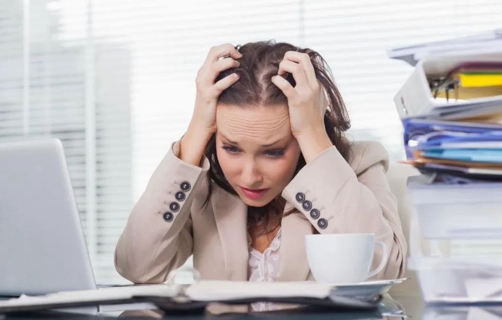 Mulher em sua mesa de trabalho tensa olhando para os reltórios