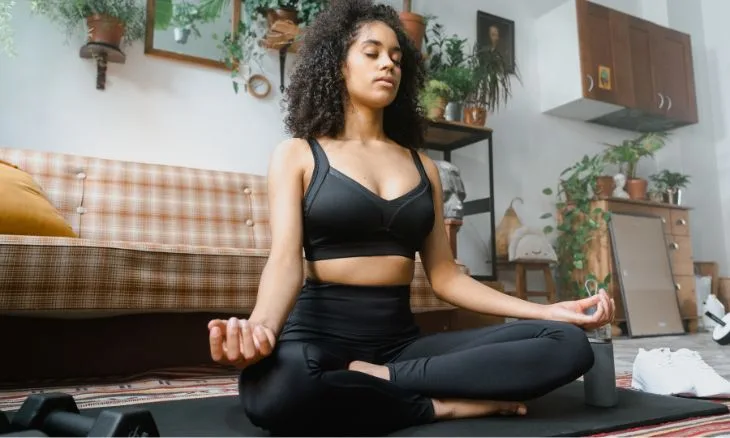 mulher sentada em posição de meditação na sala