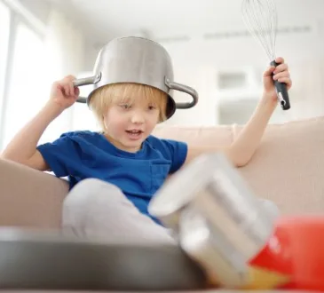 Menino com uma panela na cabeça brincando e fazendo barulho