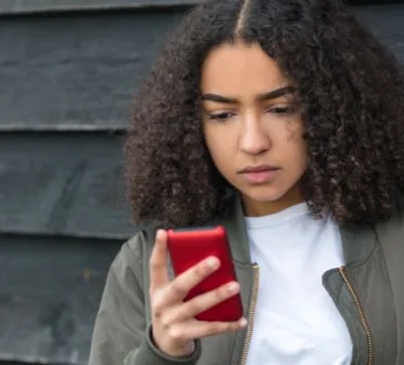 Menina adolescente com olhar de surpresa vendo a mensagem no seu celular